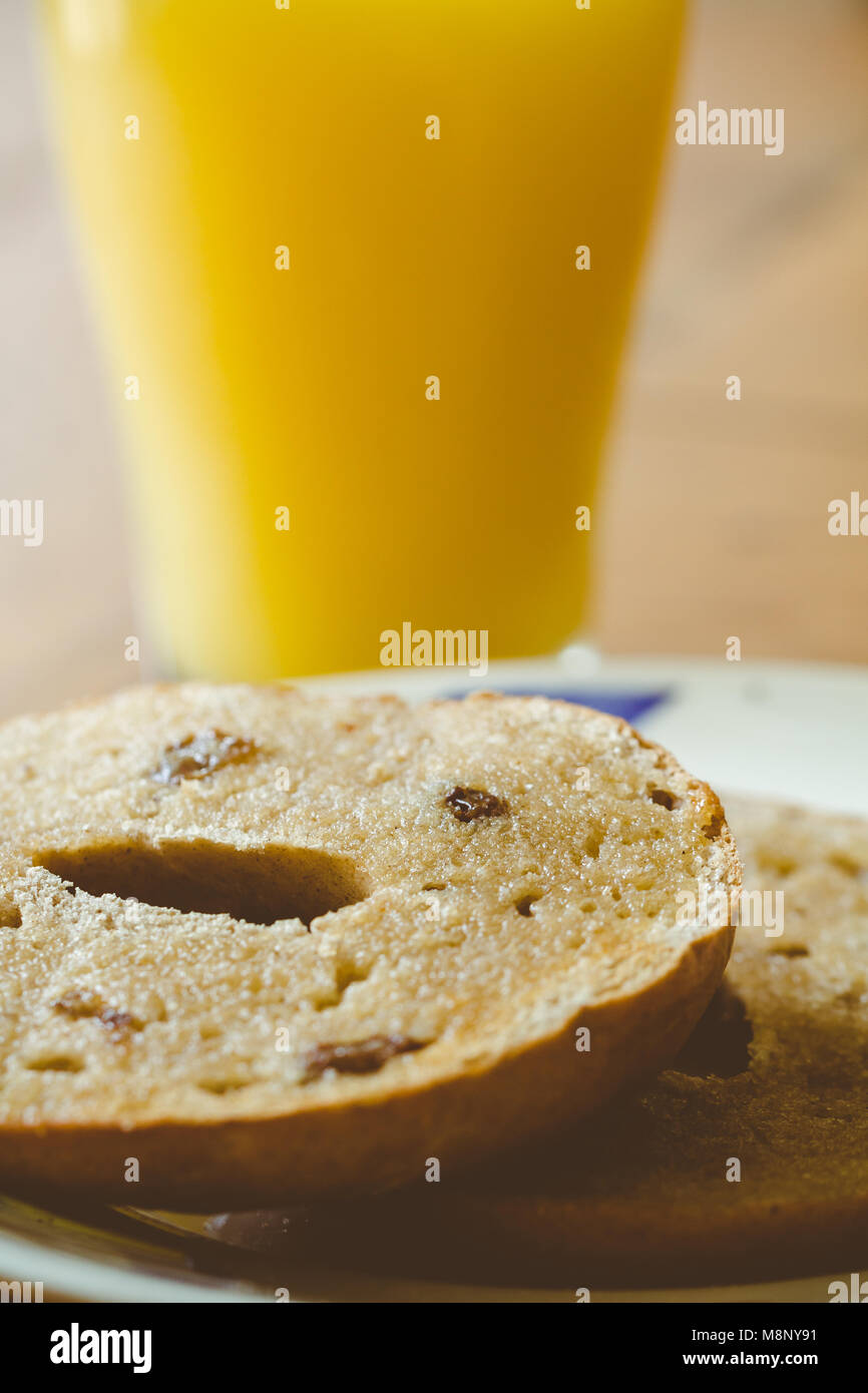 A glass of orange juice and a sliced toasted raisin and cinnamon bagel Stock Photo