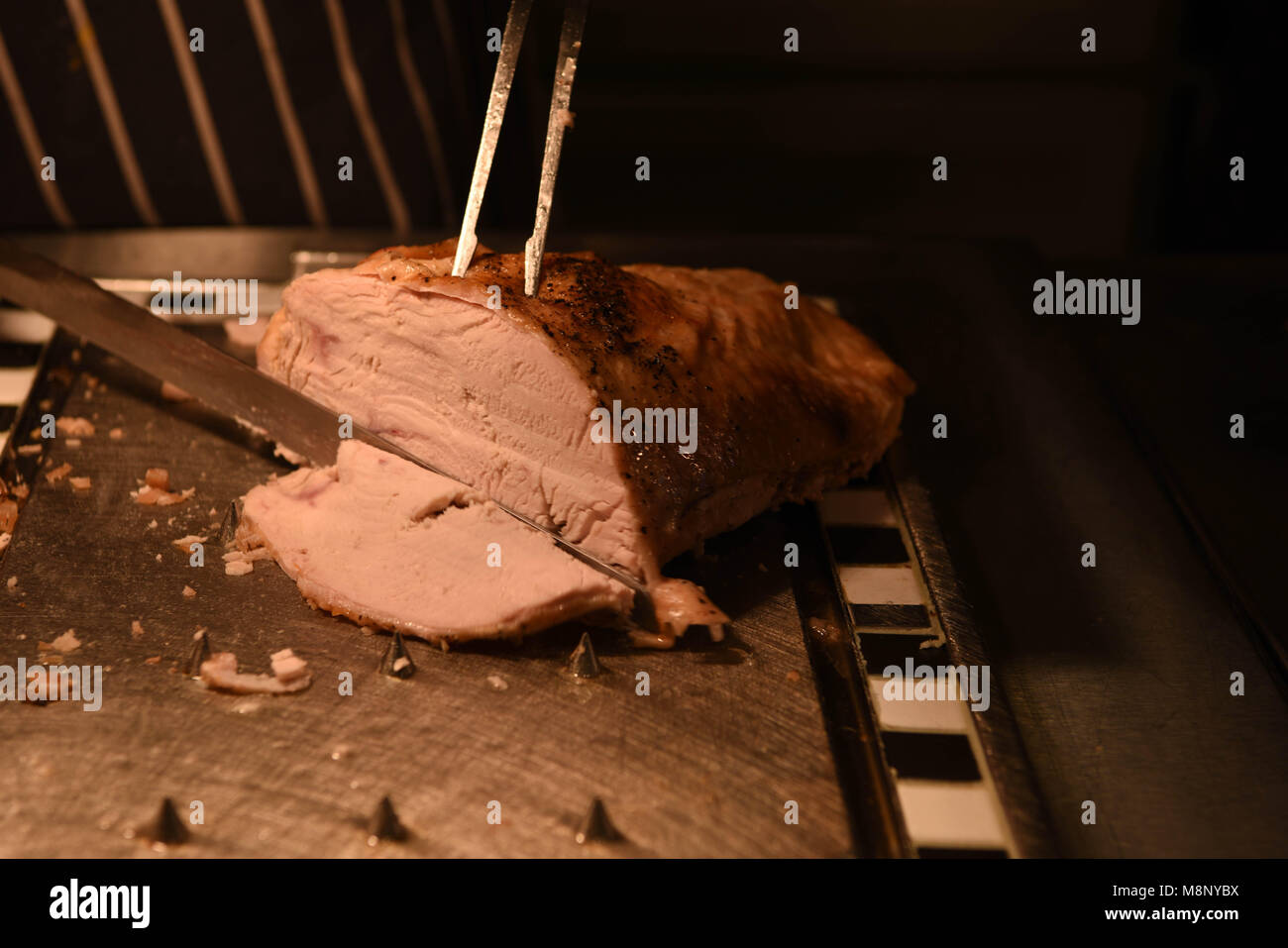 roast turkey meat being carved with carving knife and fork and chef in