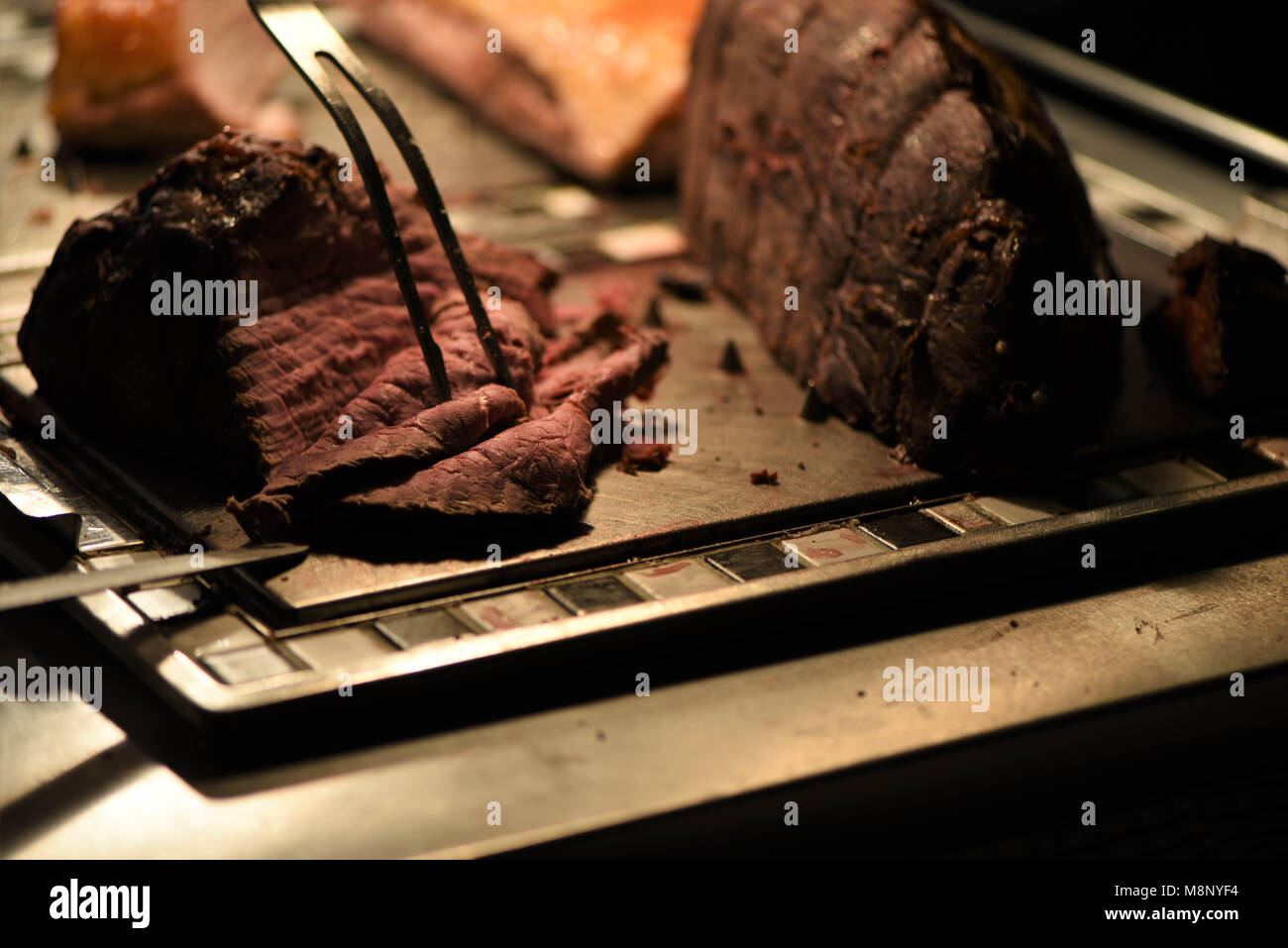 Chef Slicing Roast Beef Using Carving Knife And Fork Stock Photo