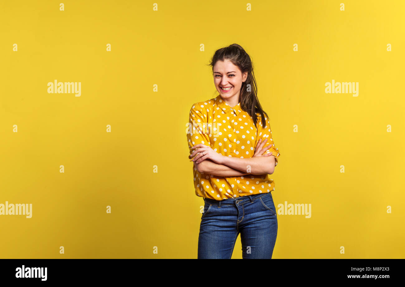 Portrait of a young beautiful woman in studio on yellow background ...