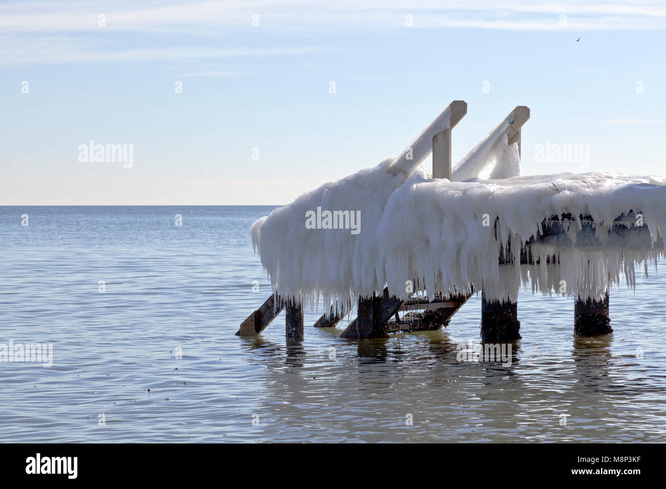 Melting ice formations and icicles on a bathing jetty at Skodsborg on an early, sunny spring day at the Sound / Oresund north of Copenhagen, Denmark. Stock Photo