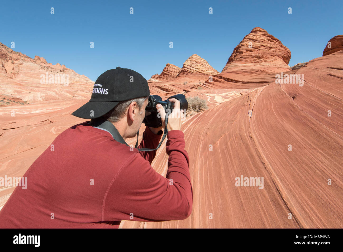 A man takes a picture of pyramid shaped sandstone formations in Coyote Buttes North. Stock Photo