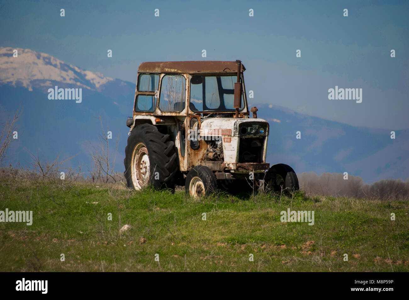 Old tractor in field with mountain background Stock Photo - Alamy