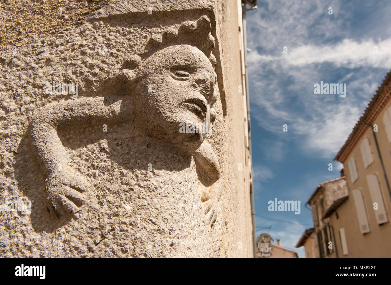 Stone masonry in Saint-Lizier, Occitanie, France: a face sculpted in stone on the corner of two historic homes in the old centre. Stock Photo