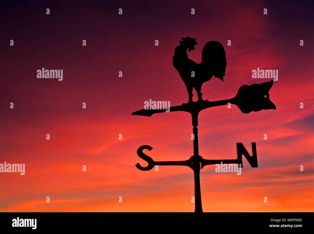 Colorful sunrise silhouette of a rooster weathervane perspective
