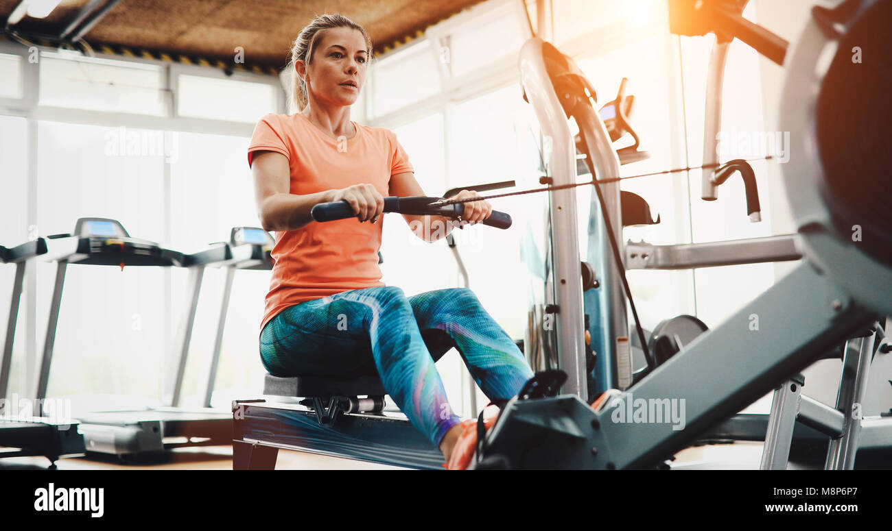 Woman pulling on row machine in fitness Stock Photo