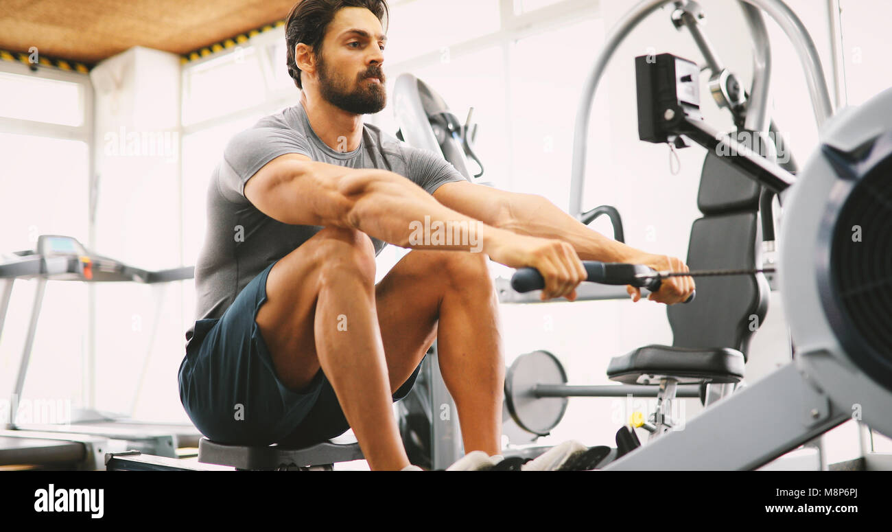 Fit man training on row machine in gym Stock Photo