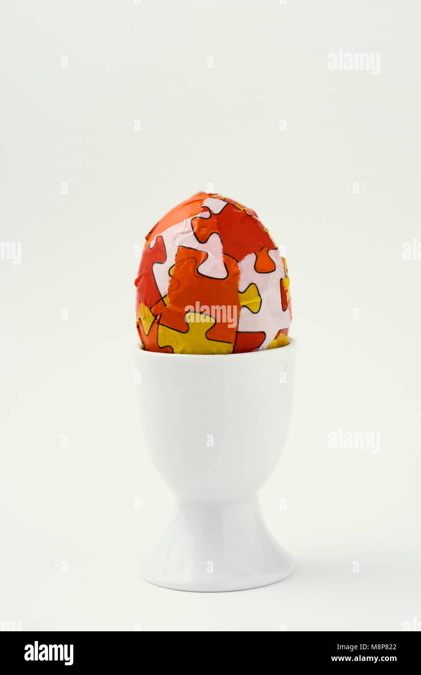 closeup of a homemade decorated easter egg, made by myself, in a white ceramic egg-cup against an off-white background, with some blank space on top Stock Photo