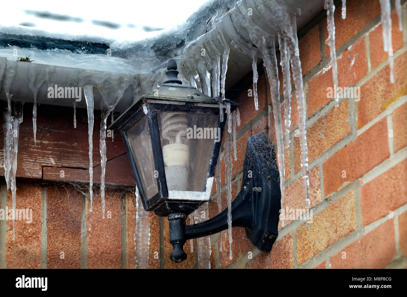 frozen icicles hanging from house gutteering during prolonged cold snap Stock Photo