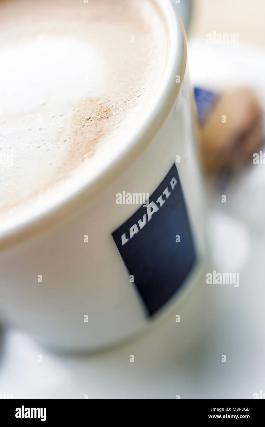 Cup of Lavazza Latte coffee in white china cup with white saucer in  daylight with froth foam on top and biscuit and teaspoon Stock Photo - Alamy