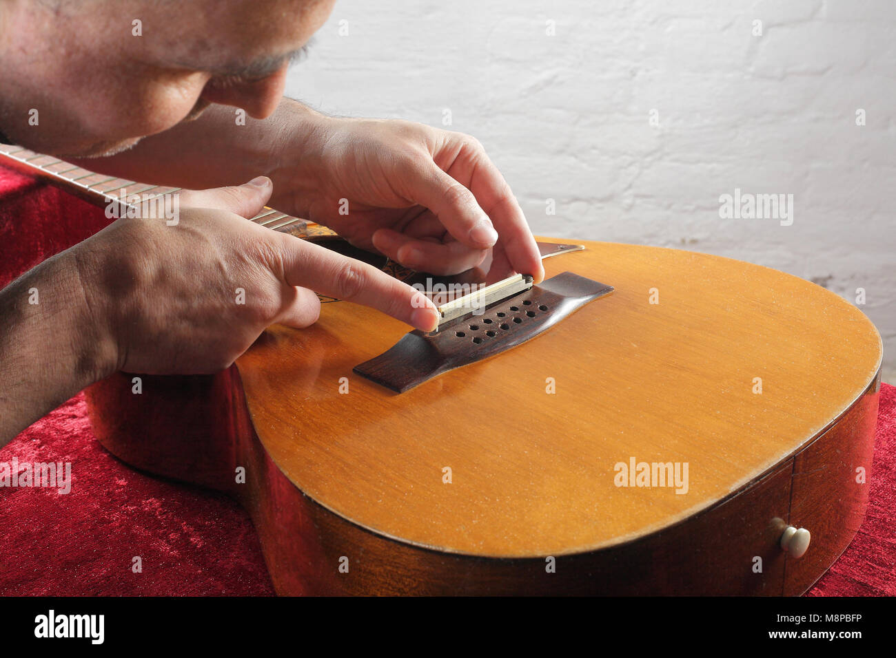 Musical instrument guitar repair and service - Grinding bridge nut. Stock Photo