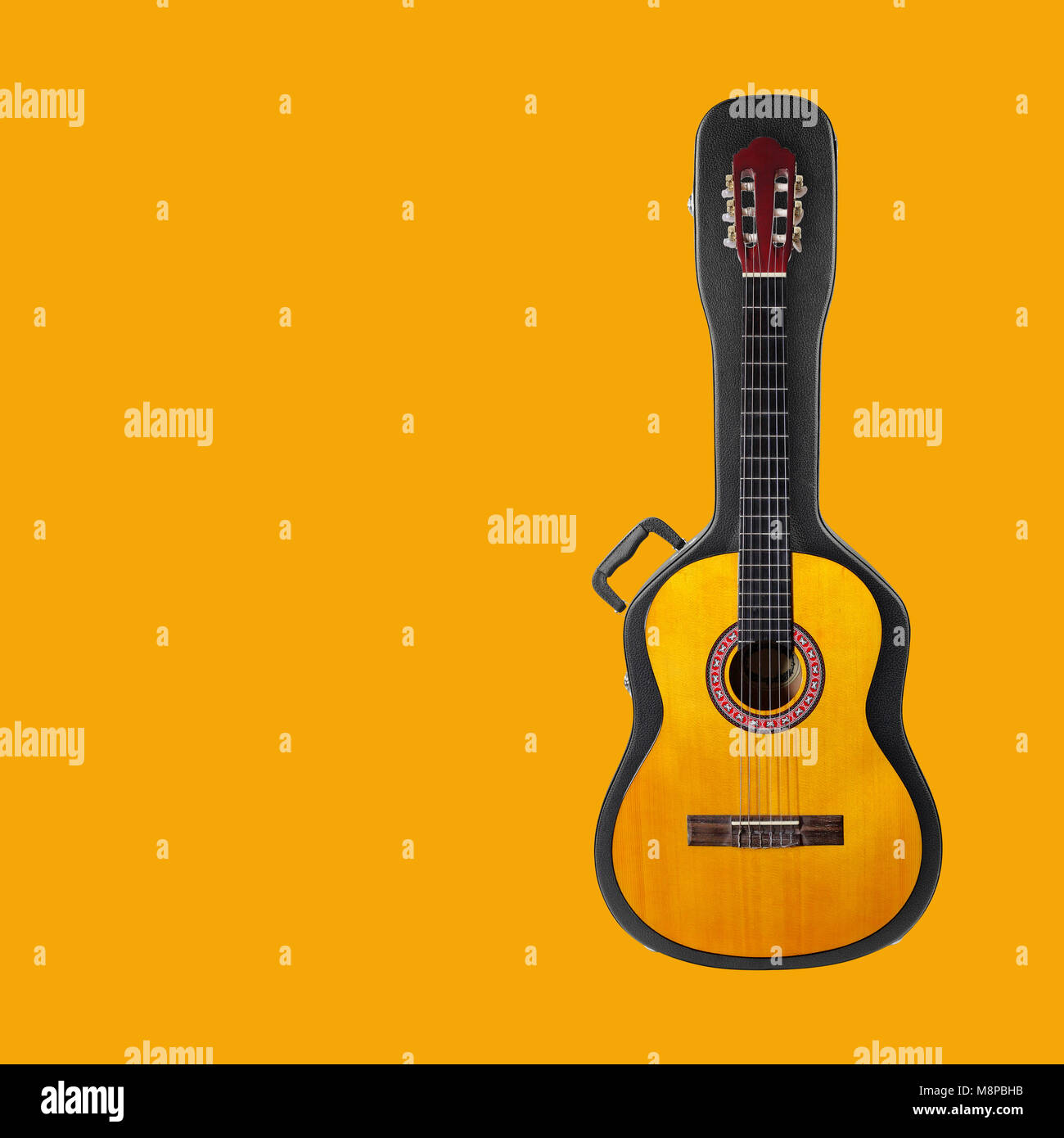 Musical instrument - Acoustic classic guitar from above on a hard case on a yellow background. Stock Photo