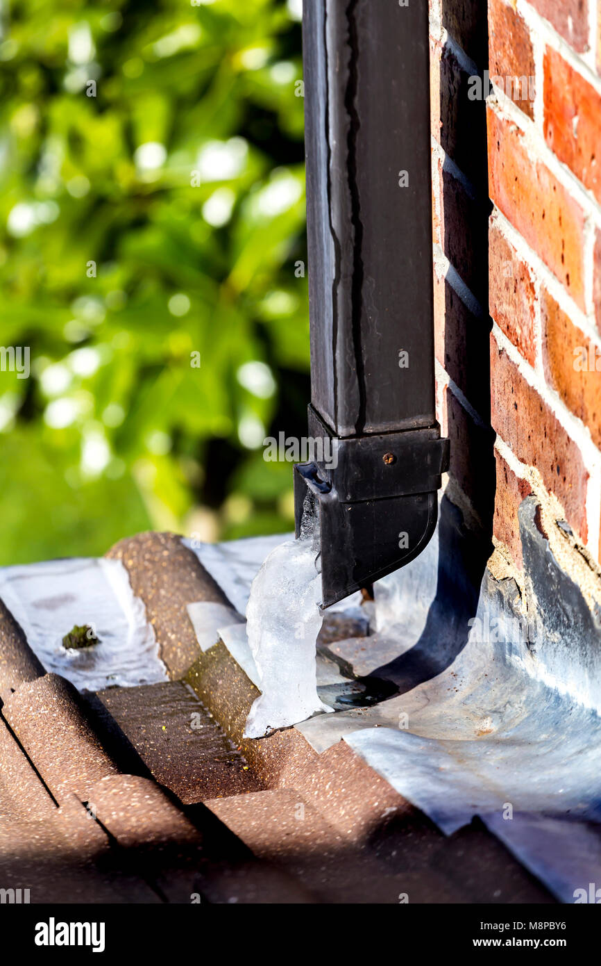 WATER FROZEN AS IT COMES OFF THE ROOF AND THROUGH THE DOWN PIPE Stock Photo