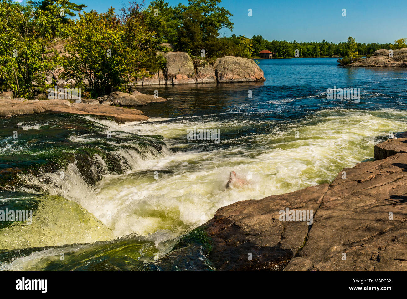 Burleigh Falls Peterborough Canada featuring river rapids with strong current and pink rocks on a beautiful summer day with blue sky Stock Photo