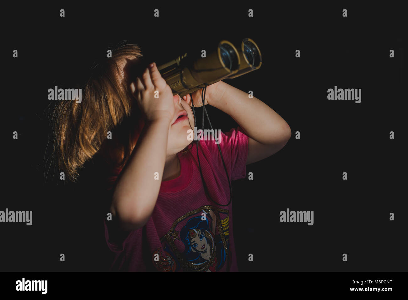 A young toddler girl looking through binoculars. Stock Photo