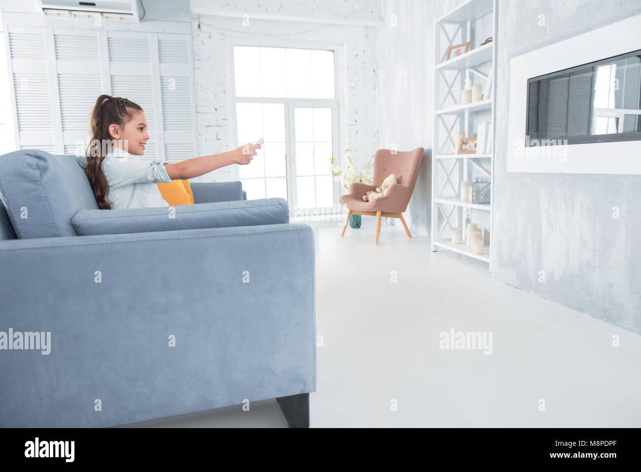 Positive happy girl using a remote control Stock Photo - Alamy