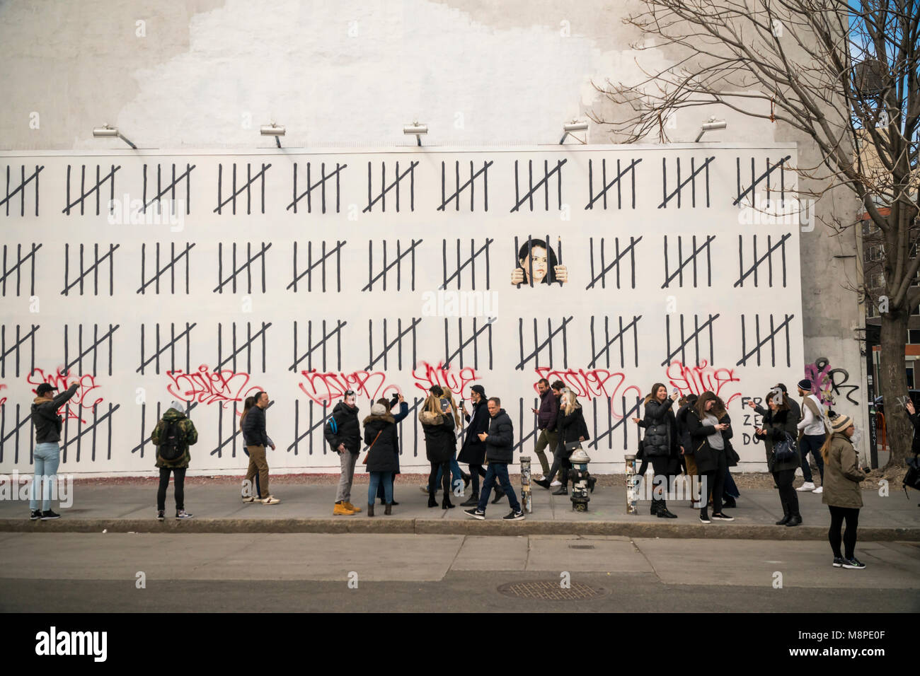 Street art enthusiasts flock to the 'Bowery Wall on Houston Street in New York on Saturday, March 17, 2018 to view and photograph artist Banksy's collaboration with the street artist Borf. The work is a tribute to the jailed Turkish Kurdish artist Zehra Dogan who was arrested for painting a work featuring a Kurdish town in ruins after a conflict between the army and Kurdish rebels.  Banksy's work previously appeared in New York on October 2013 when he created a work a day during his one month 'residency'. (Â© Richard B. Levine) Stock Photo