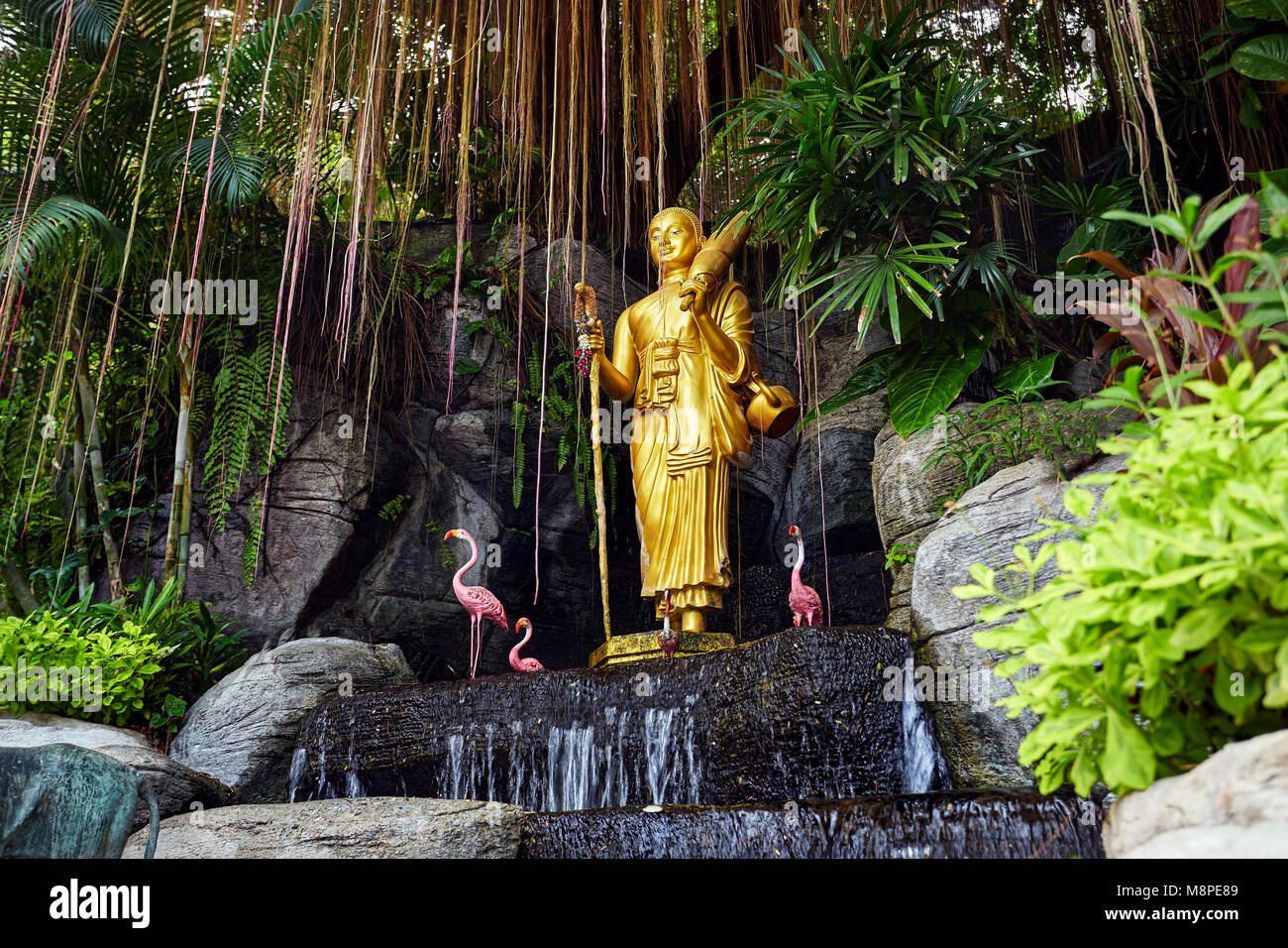 Golden Buddha statue in the tropical garden with waterfall in Wat Saket Golden Mountain Temple in Bangkok Stock Photo