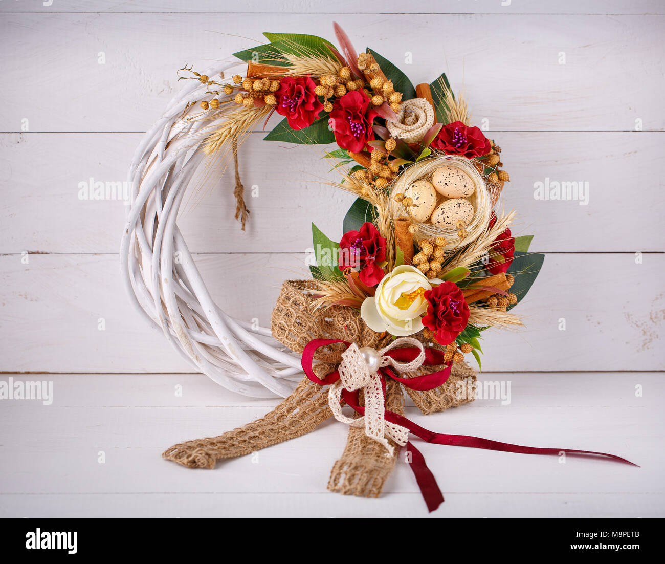 Decorative woven wreath is decorated with flowers and quail eggs. Wreath for pecker's Easter holidays Stock Photo