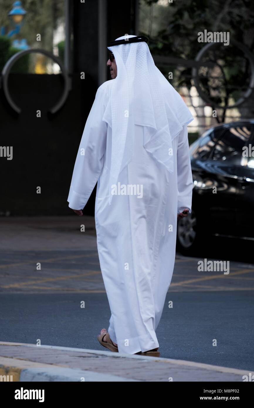 A local Emirati man in local Arab traditional dress walking near Hamdan Street Abu Dhbi Stock Photo