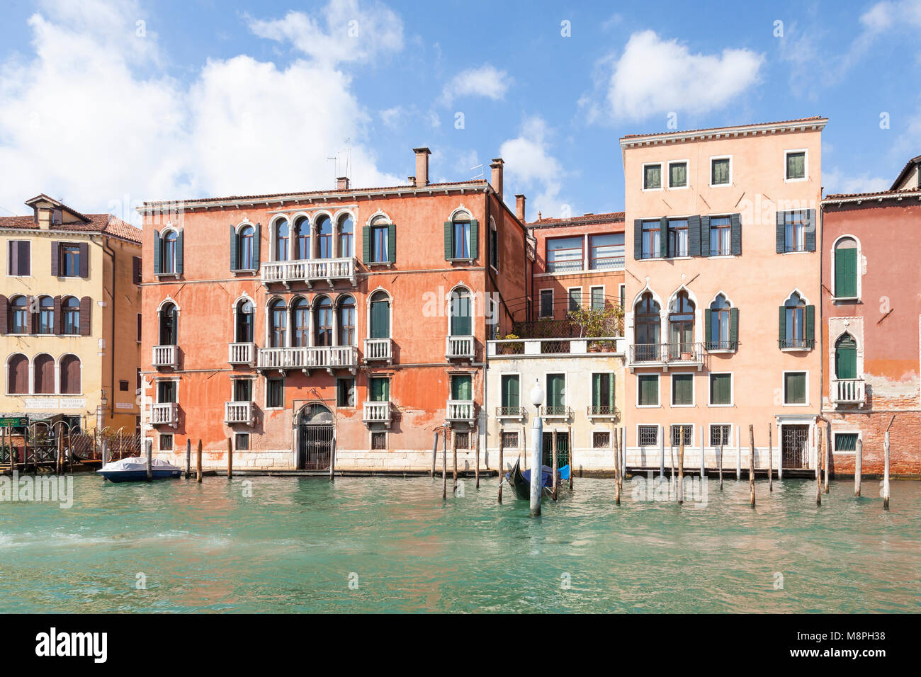 Palazzo Giustinian Persico (red left) and Palazzo Tiepolo Passi, Grand Canal, San Polo, Venice, Veneto, Italy on a blue sky sunny day with cloud Stock Photo