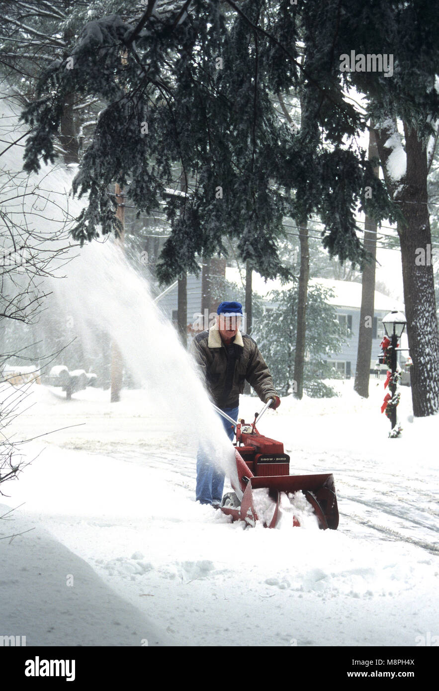 A man snowblowing his driveway Stock Photo