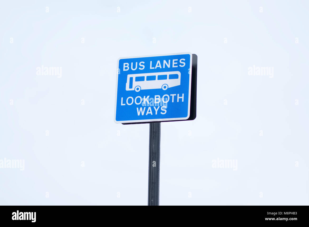 Bus lanes look both ways fixed penalty fine sign post in large open pale blue sky Stock Photo