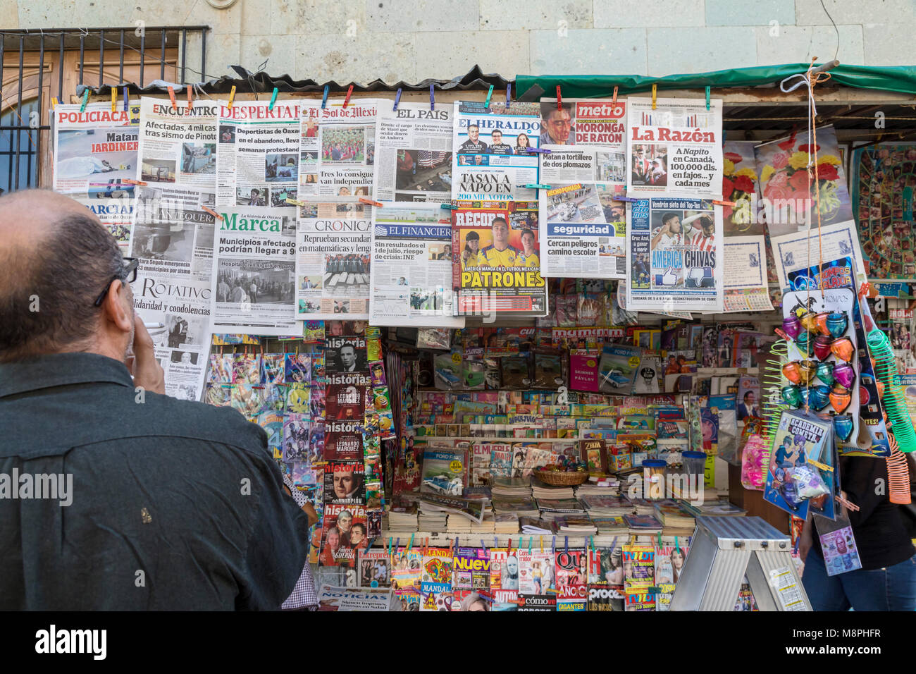 Oaxaca, Oax., Mexico - A man reads the headlines of the many newspapers on sale at a newsstand. Stock Photo