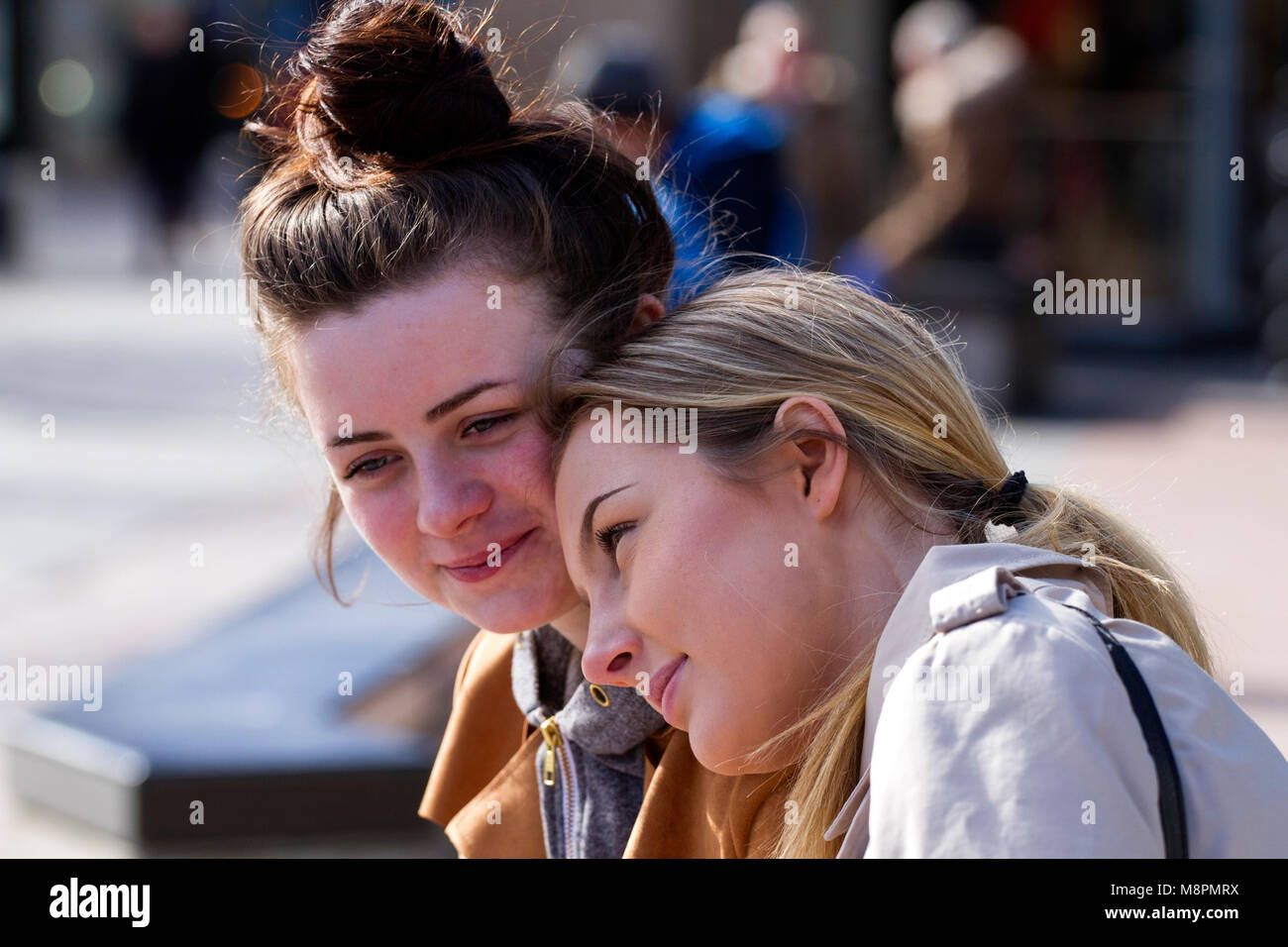 Dundee, Tayside, Scotland, UK. 19th March, 2018. UK weather: Two young female friends seated close together enjoying the mild sunny spring day in Dundee city centre, UK. Credit: Dundee Photographics / Alamy Live News Stock Photo