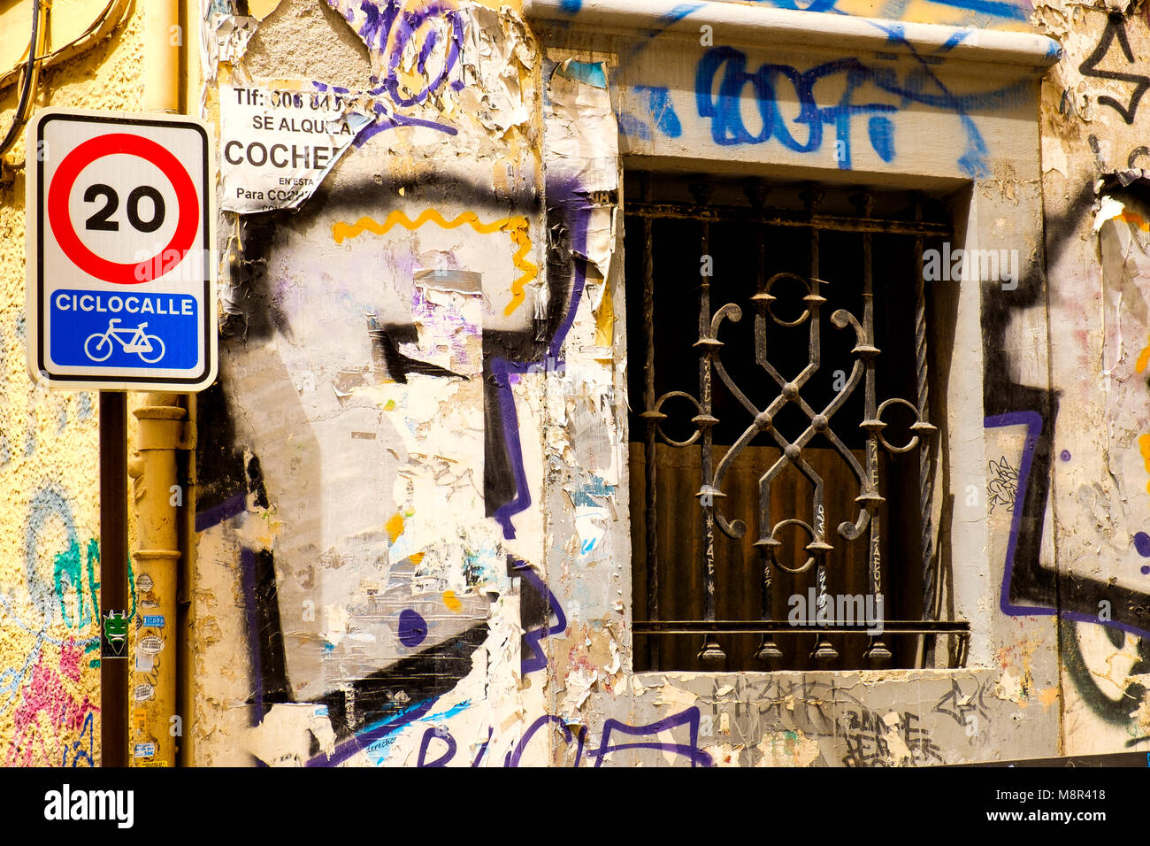 Graffiti mixes with flaking plaster and concrete on a delapidated building on a residential street in the north centre of the city of Granada (on or a Stock Photo