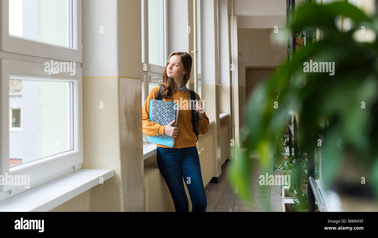 Window Alone Student Young attractive female high school student standing by the window in ...