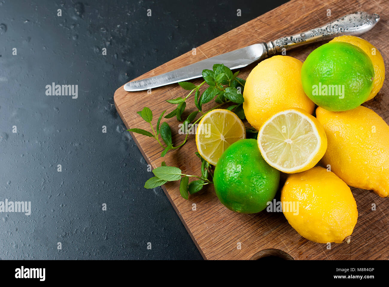 Top view of lemons and limes with mint on wooden kitchen board, barman