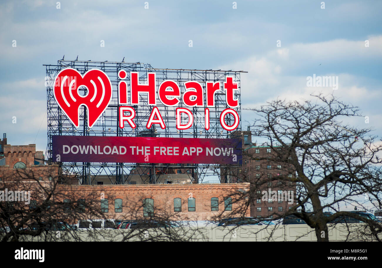 A giant billboard in the Bronx, in New York faces Manhattan and advertises iHeartMedia on Thursday, March 15, 2018. iHeartMedia is the largest owner of radio stations in the U.S. and has filed for Chapter 11 bankruptcy protection which will half its $20 billion in debt and transfer 91 percent of its stock to its creditors. (© Richard B. Levine) Stock Photo