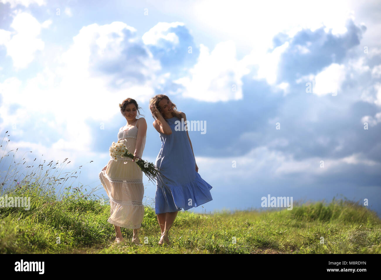 Young girls are walking in the field Stock Photo - Alamy