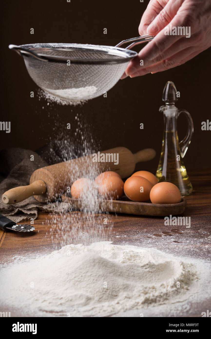 sifting flour from a strainer on a wooden table Stock Photo Alamy