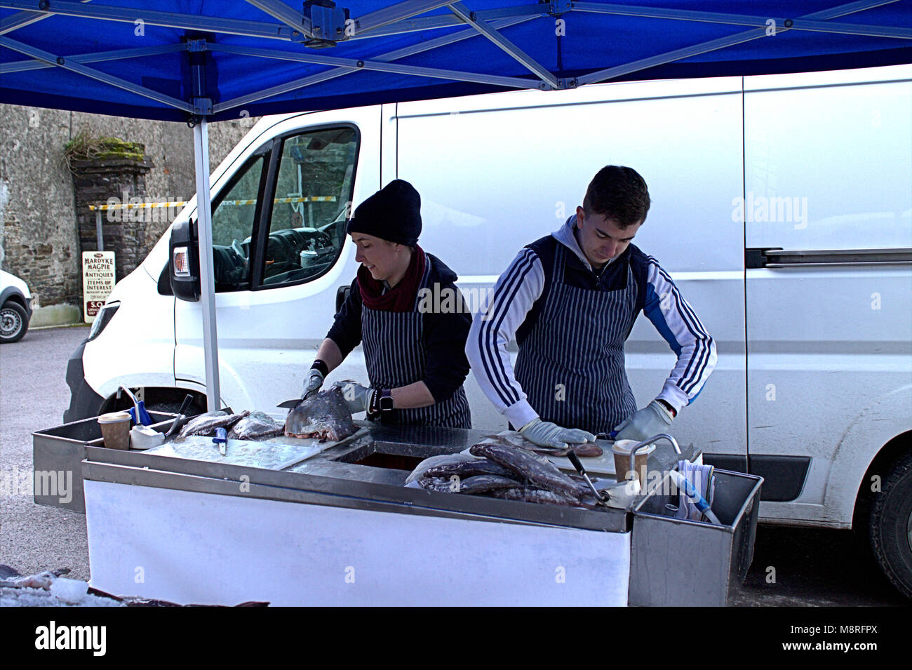 young fishmongers gutting fish on their fish stall at the local weekly food market in skibbereen, west cork. Stock Photo