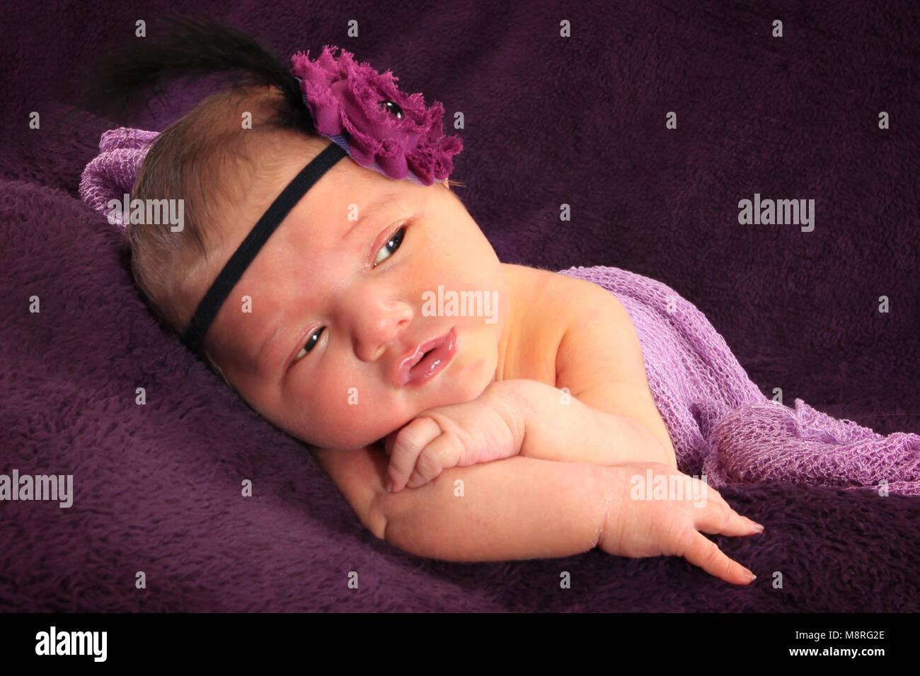 cutie newborn baby girl in swaddling wrap on soft blanket in nursery, beautiful princess Stock