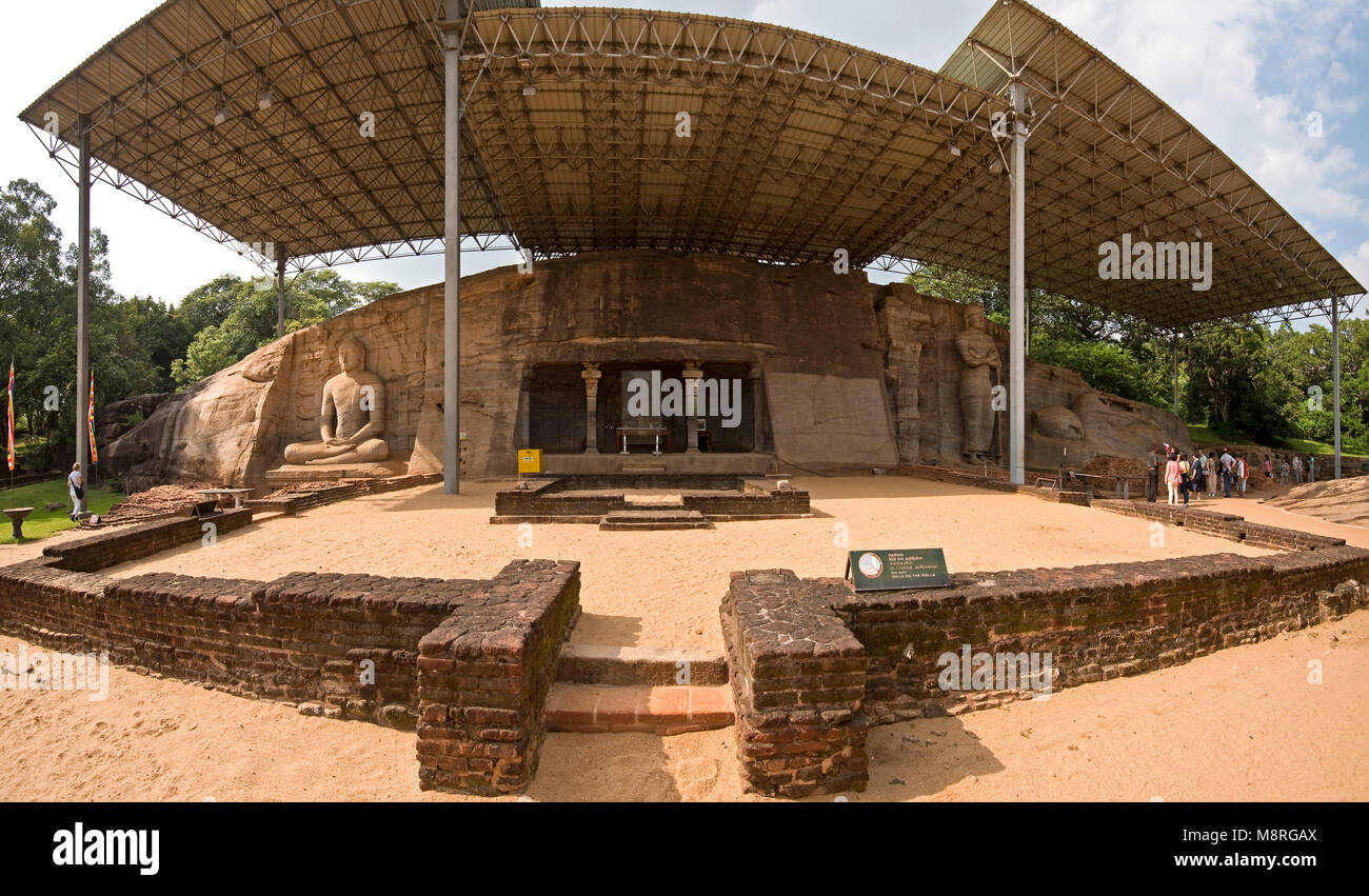 A 2 picture stitch panoramic of the Buddha figures at Gal Vihara in Polonnaruwa, Sri Lanka on a sunny day with blue sky and tourists walking around. Stock Photo