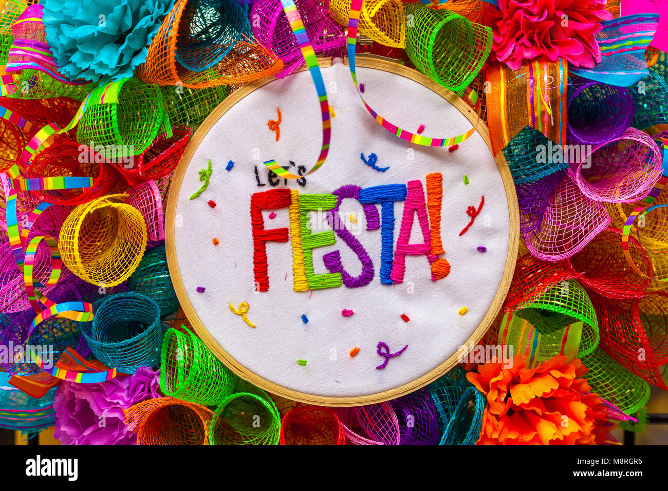 The word 'fiesta' stitched in colorful letters on multicolored mash decorated with glitter and paper flowers Stock Photo