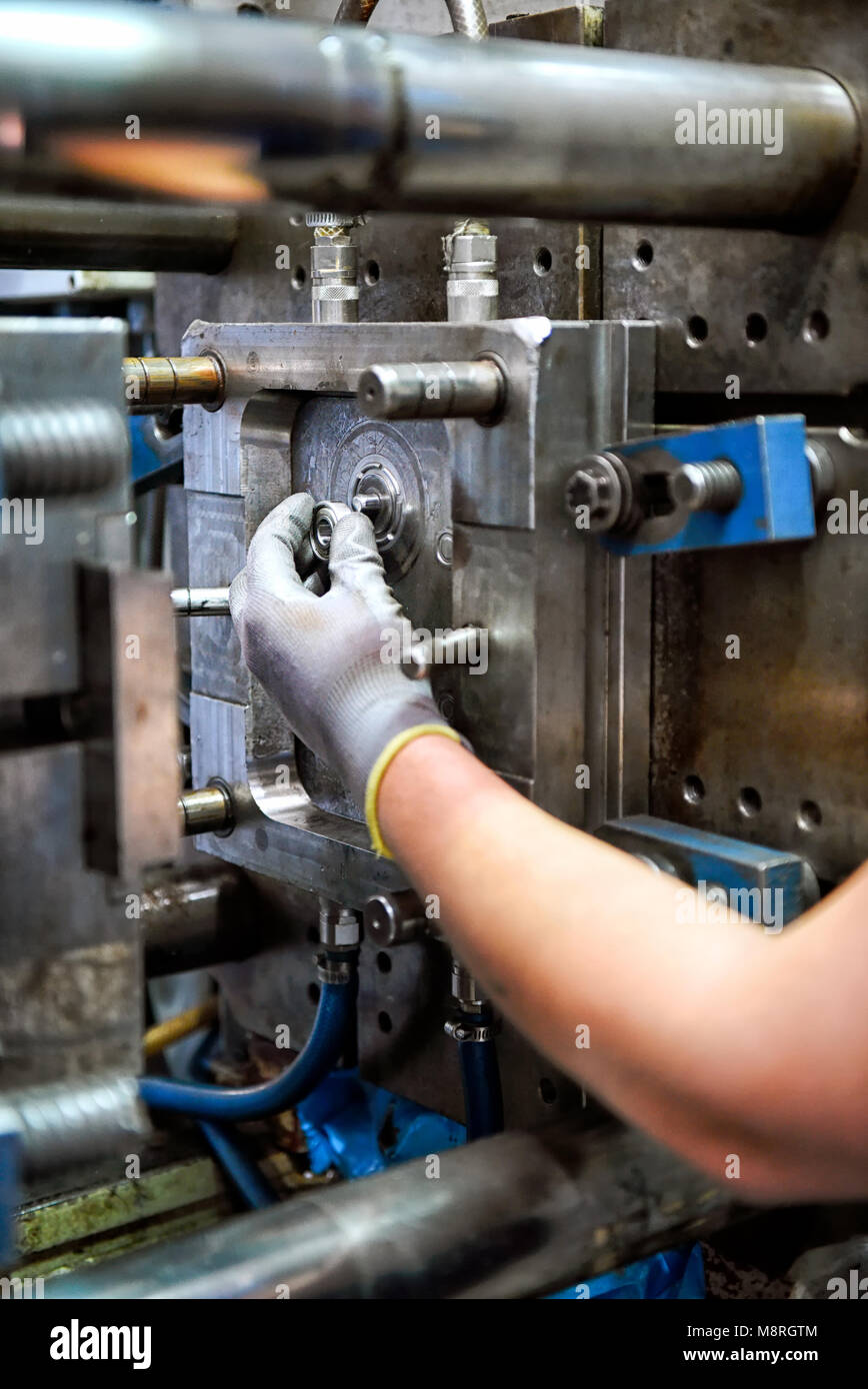 Man blue-collar employee working on repairing metalworking machine, one hand in glove viewed in close-up Stock Photo