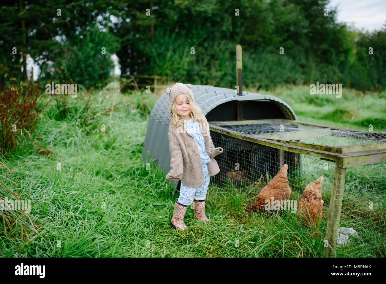smiling little blond girl playing outside in the mud Stock Photo