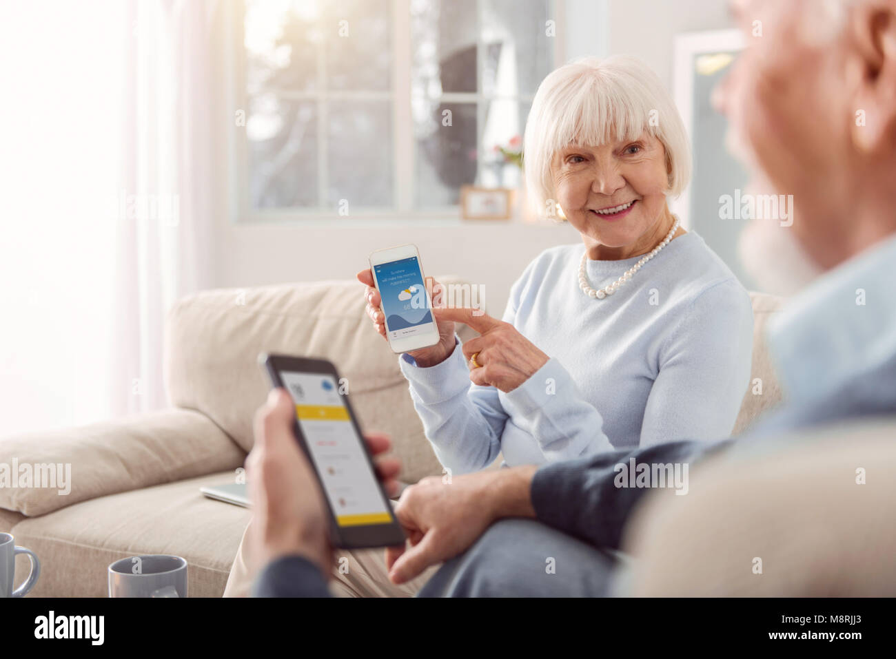 Upbeat senior woman showing weather app to her husband Stock Photo