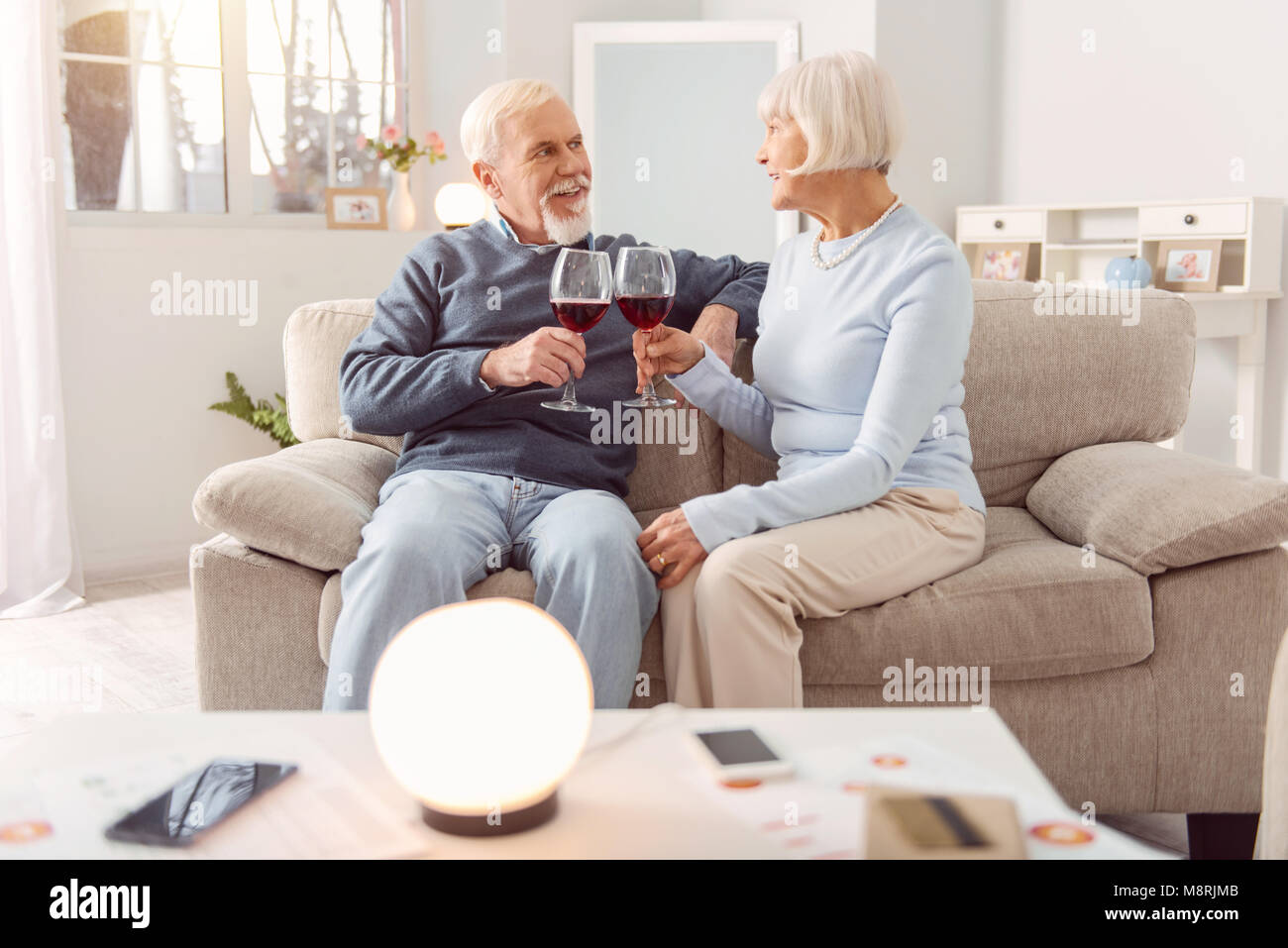 Happy elderly couple drinking wine on couch Stock Photo - Alamy
