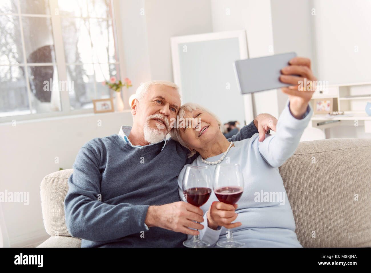 Cheerful elderly couple taking selfie while drinking wine Stock Photo ...