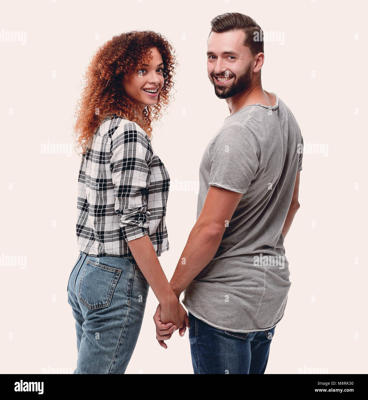 Rear view of happy couple holding hands and looking at camera Stock ...
