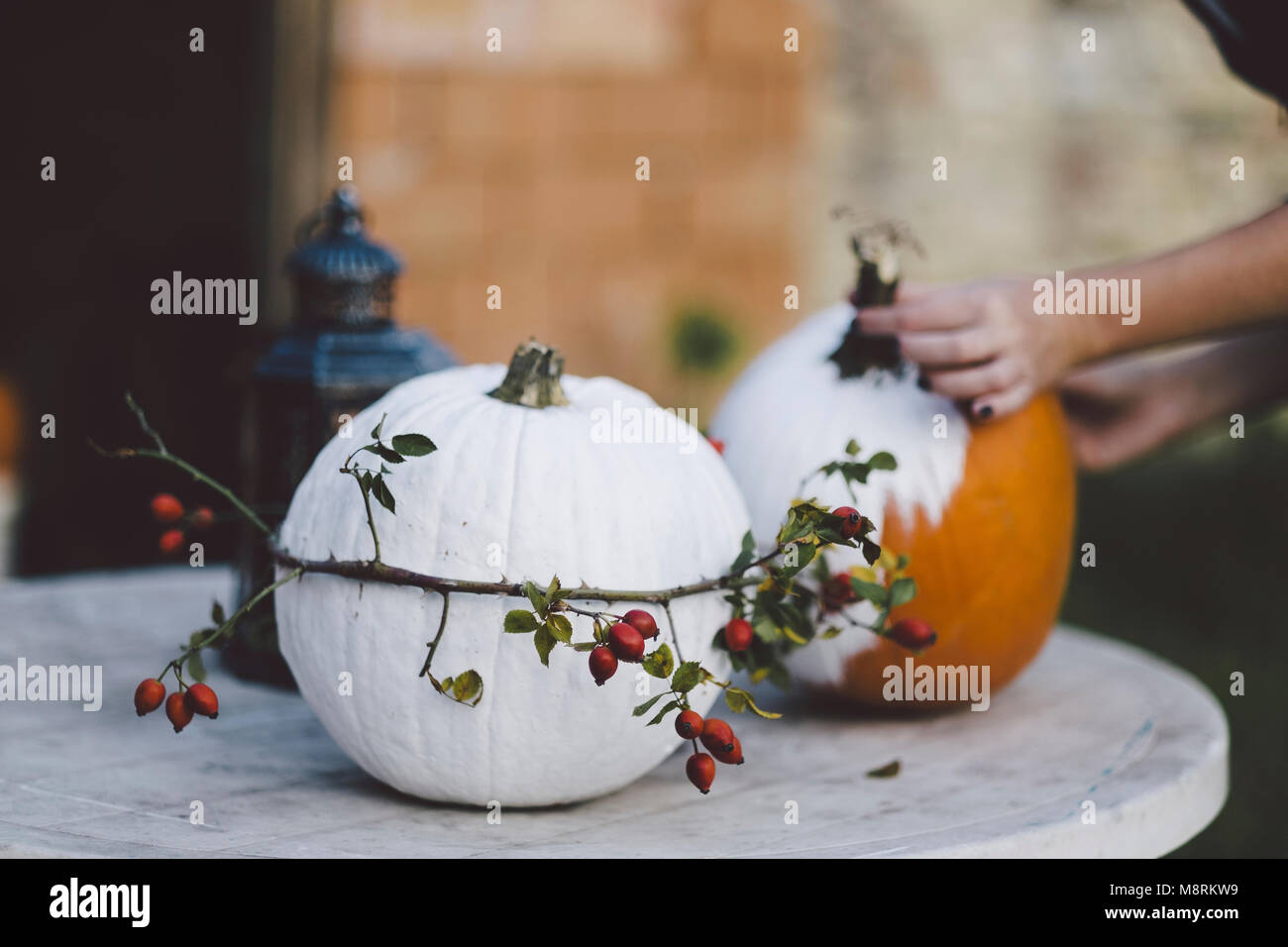 Cropped hands of woman making Halloween pumpkins on table at yard Stock Photo