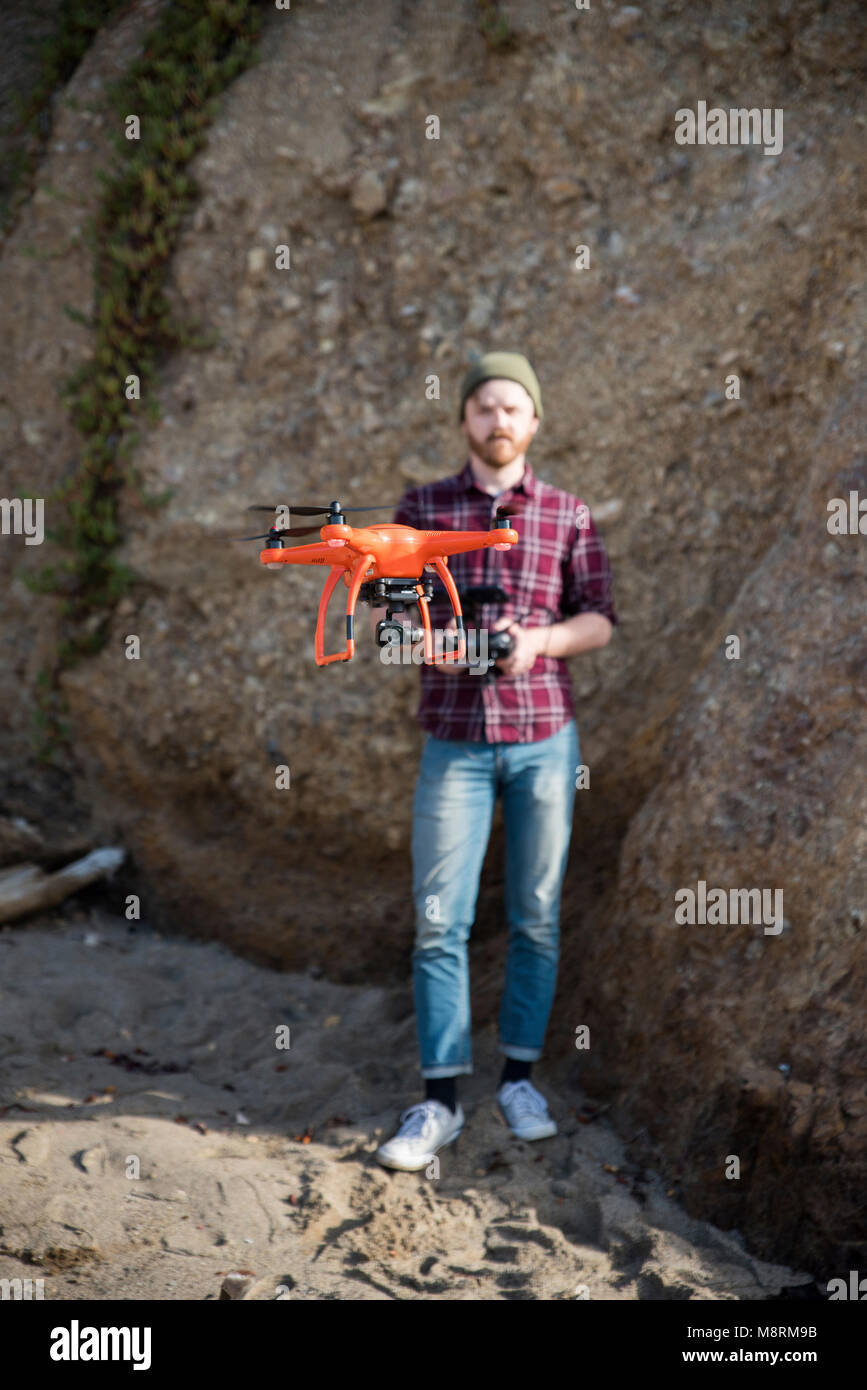 Full length of man flying drone while standing against rock formation Stock Photo