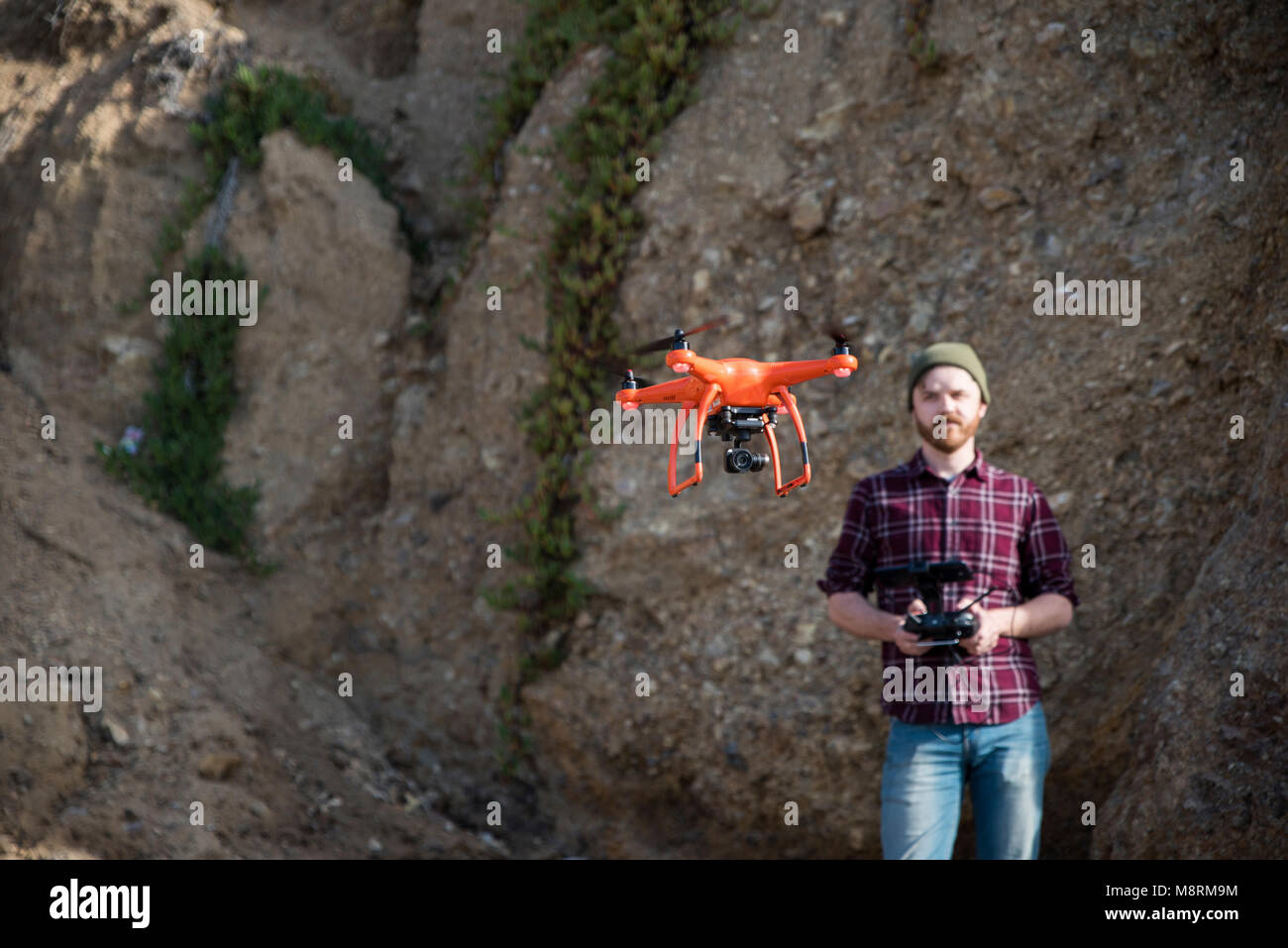 Man flying drone while standing against rock formation Stock Photo