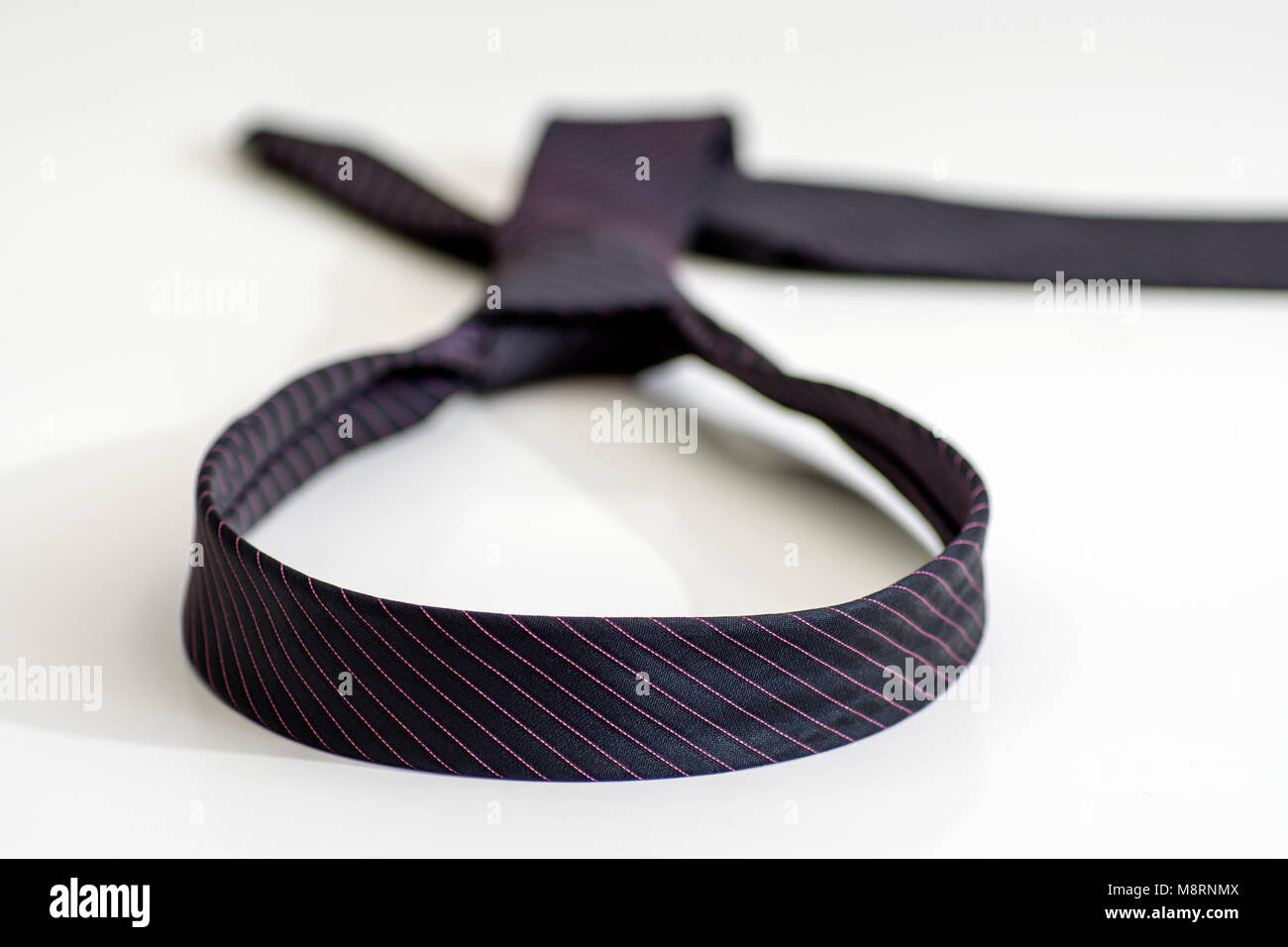 black tie knotted in a loop shape on a white background. The concept of not freedom Stock Photo