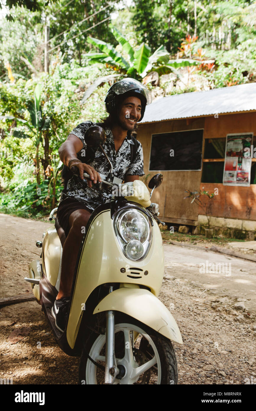Cheerful man wearing helmet while driving motor scooter on dirt road Stock  Photo - Alamy